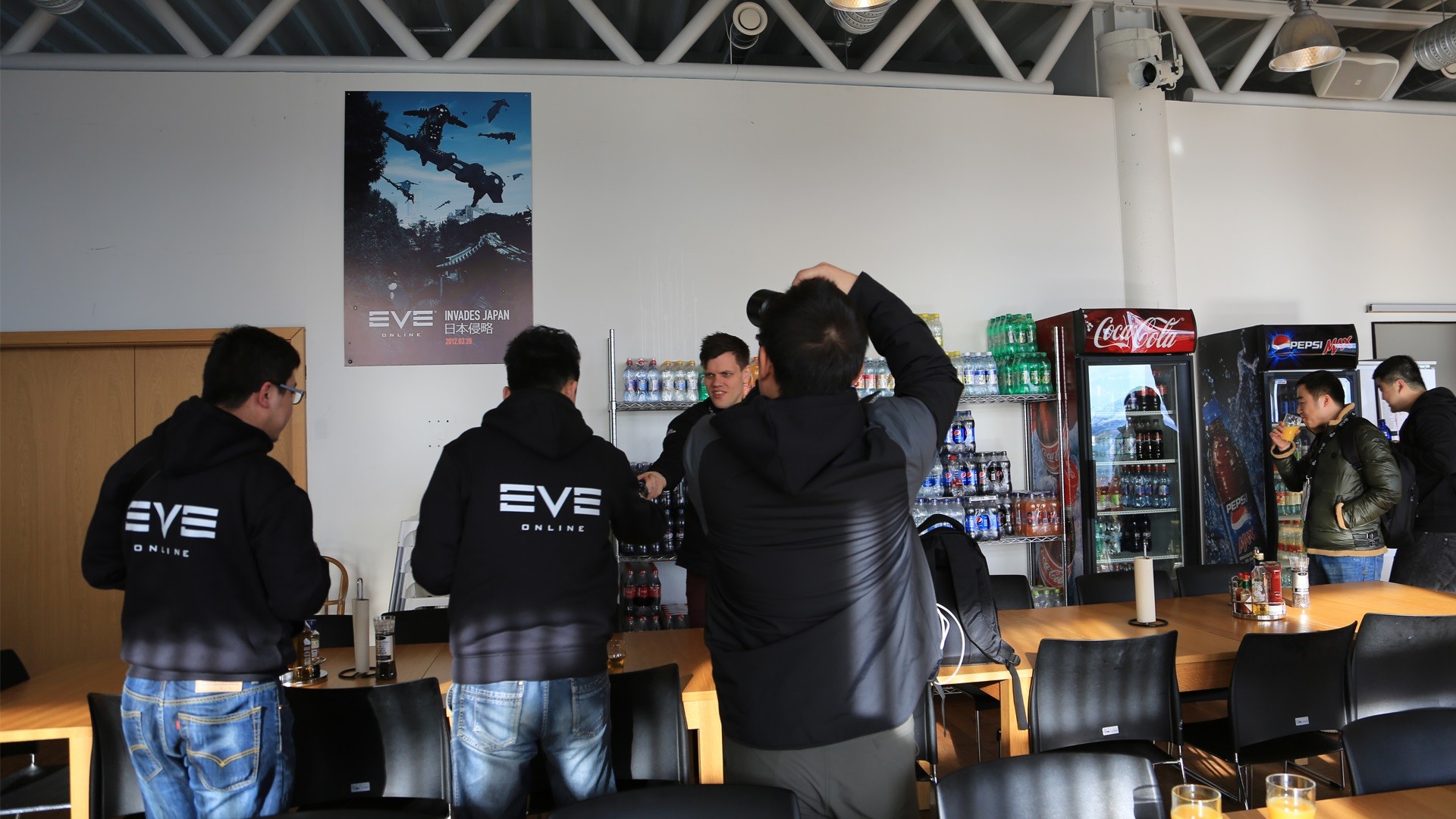 COA的队员们对于CCP食堂墙上的这幅日本侵略海报非常感兴趣。当然除了这张独特的海报之外，还有酷菲可以喝到。陪同队员的CCP工作人员Burger正在递上酷菲饮料。（真的不是尸体做的！）